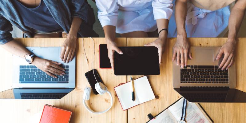 One man and two woman sitting with their laptop and tablet
